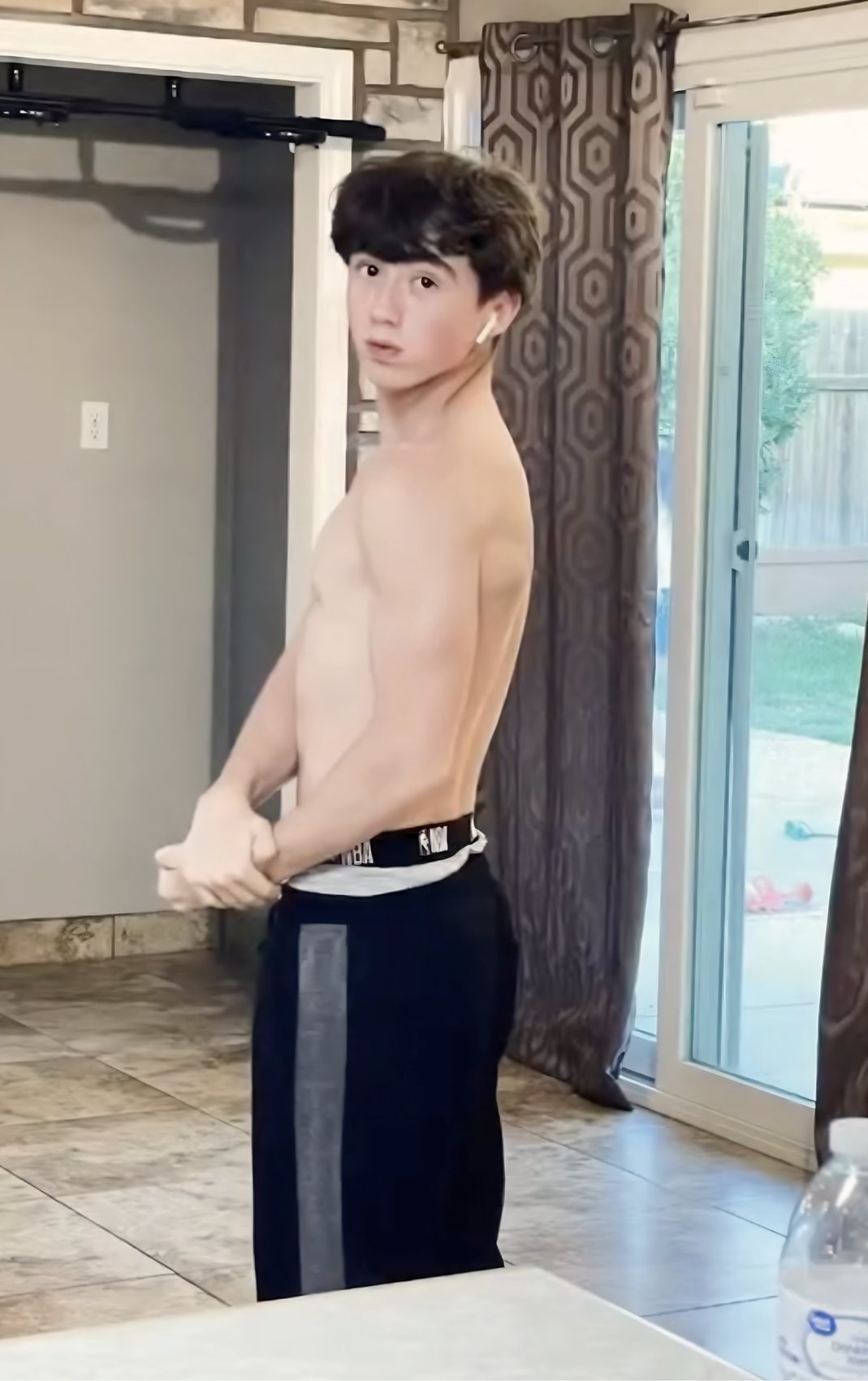 Before: skinny build under a doorway pull-up bar at home, day one of calisthenics
